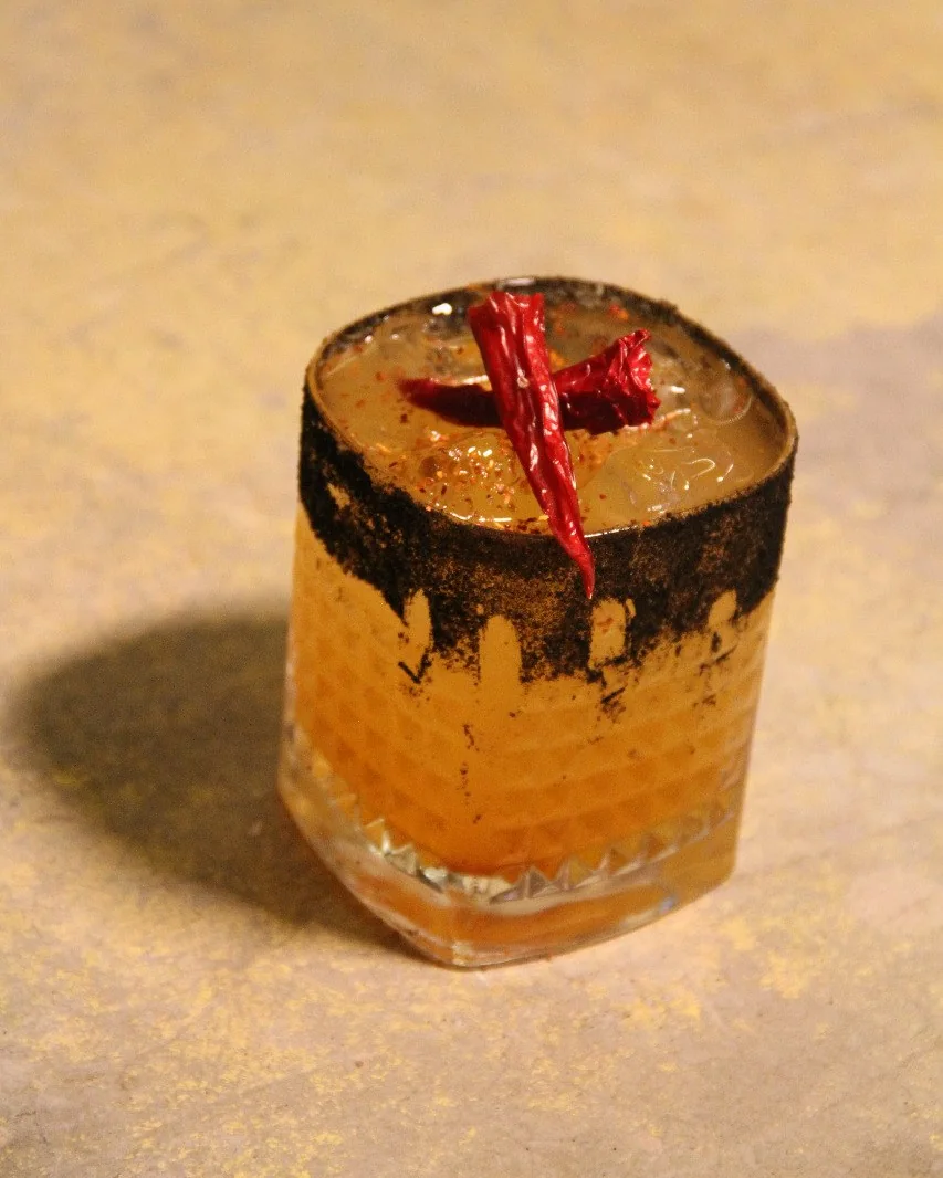Tierra Ardiente, cóctel de mezcal con piña y chile piquín, borde de ceniza de tortilla con Tajín, en Cádiz Restaurante